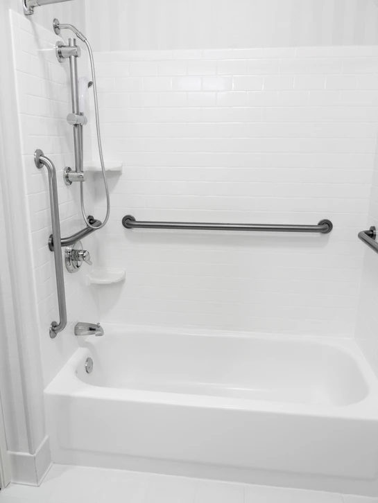 Salle de bain adaptée avec baignoire blanche équipée de barres d'appui murales en acier inoxydable