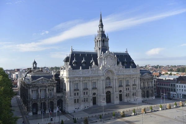 Photographie d'une rue caractéristique de Roubaix, montrant l'architecture urbaine typique de la ville du nord, avec des façades de bâtiments résidentiels ou commerciaux, prise en pleine journée avec un bon éclairage naturel, représentative du tissu urbain où VERPLANCK intervient.