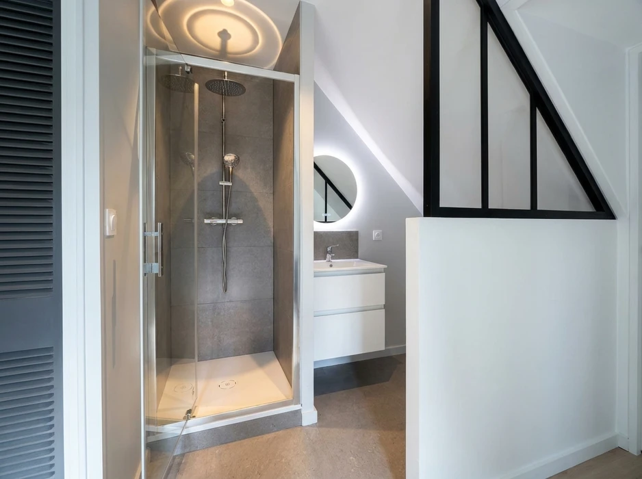 Salle de bains moderne avec double vasque encastrée sur meuble suspendu en bois foncé à 4 tiroirs, plan vasque en résine blanche