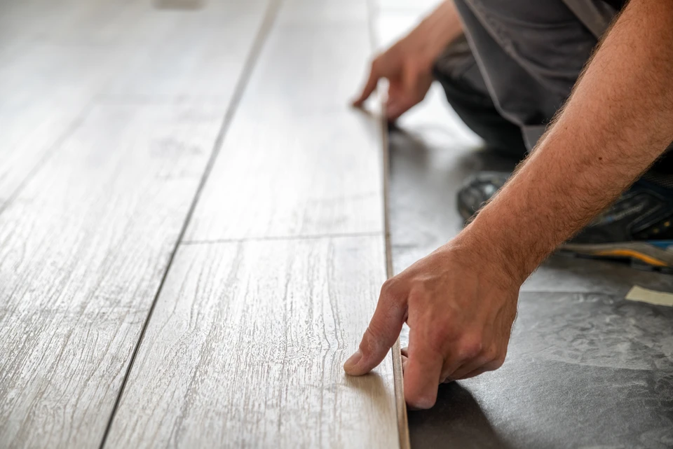 Ouvrier peintre en bâtiment appliquant un enduit gris sur mur intérieur
