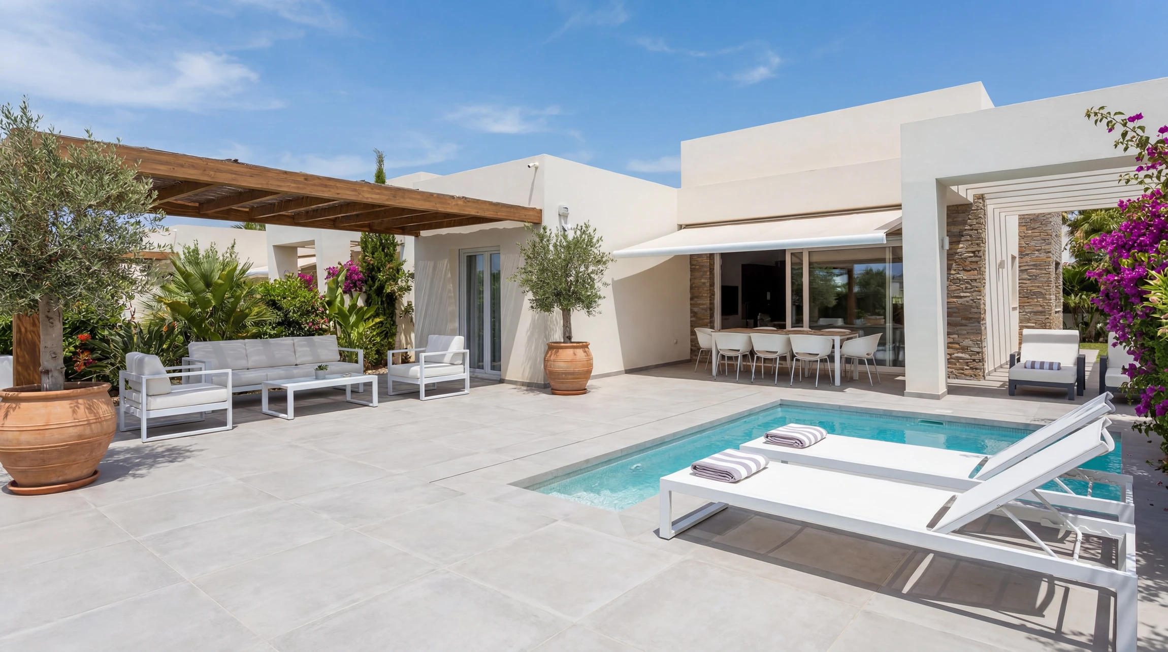 Terrasse extérieure moderne avec piscine rectangulaire à débordement, salon de jardin en rotin tressé marron avec coussins beiges disposé sous pergola bioclimatique à lames orientables blanches