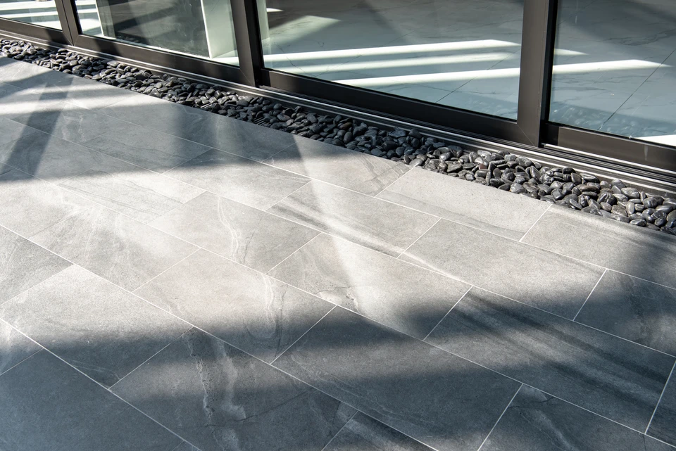 Ouvrier en équipement de protection individuelle utilisant une carrelette manuelle pour découper du carrelage sur chantier de construction
