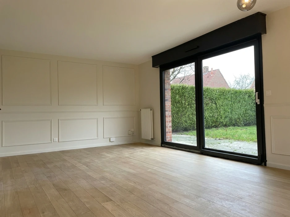 Intérieur de chantier, artisan à genoux installant du parquet massif